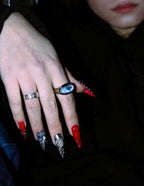 Close-up of Steel Hearts stiletto press-on nails with chunky silver rings