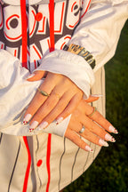 Love Notes nude French press-on nails with heart details over a baseball jersey