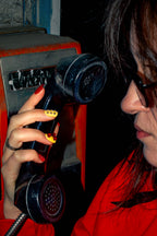 Model in a red jacket on a vintage payphone wearing Chrome Hearts press-on nails