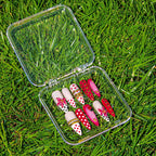 Early Bloom press-on nail set in its clear case, lying in grass