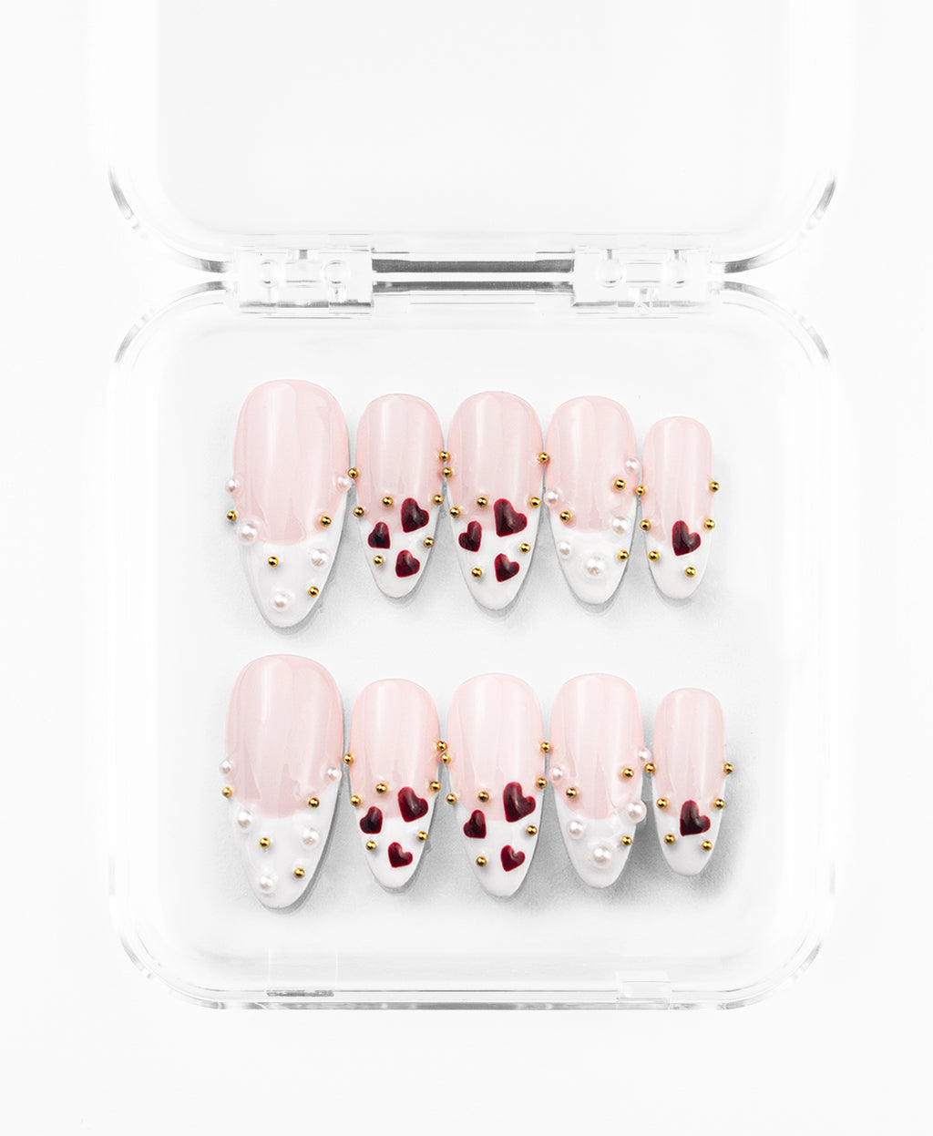 Minimalist press-on nails set featuring a refined nude and white French tip design on elongated almond nails. The set is defined by its clean, classic base accented with 3D deep-burgundy heart charms and a delicate scattering of tiny gold and pearl studs. Each nail balances sophisticated negative space with tactile luxury, offering a modern, romantic aesthetic that is both timeless and intricately detailed.