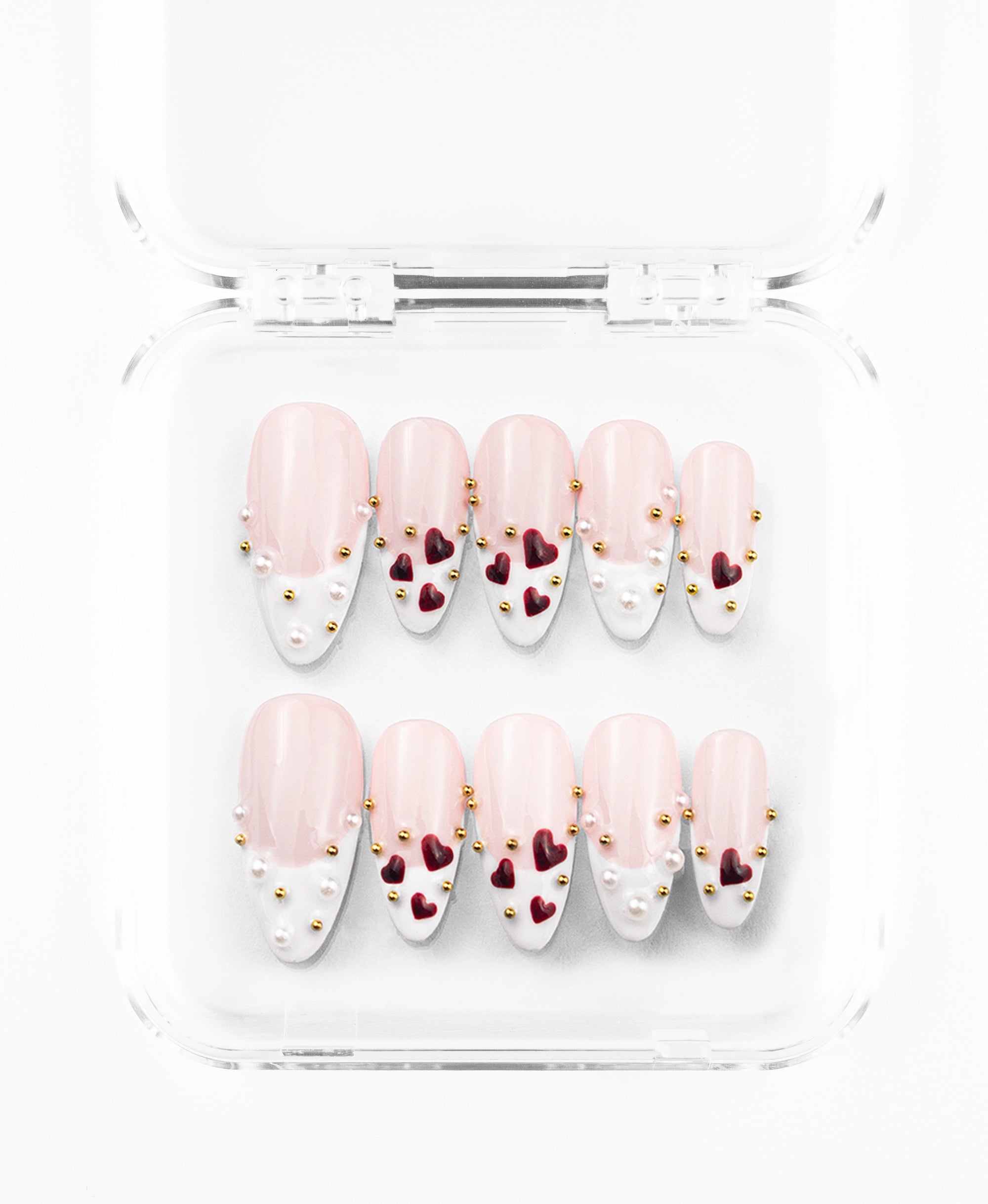 Minimalist press-on nails set featuring a refined nude and white French tip design on elongated almond nails. The set is defined by its clean, classic base accented with 3D deep-burgundy heart charms and a delicate scattering of tiny gold and pearl studs. Each nail balances sophisticated negative space with tactile luxury, offering a modern, romantic aesthetic that is both timeless and intricately detailed.