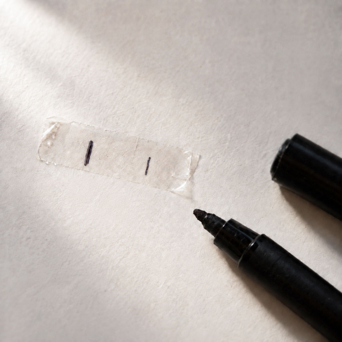 Adhesive sizing strip marked with a black marker to measure nail width