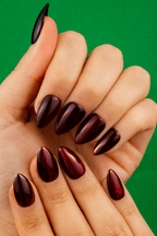 Deep Rose burgundy shimmer almond press-on nails on a green backdrop