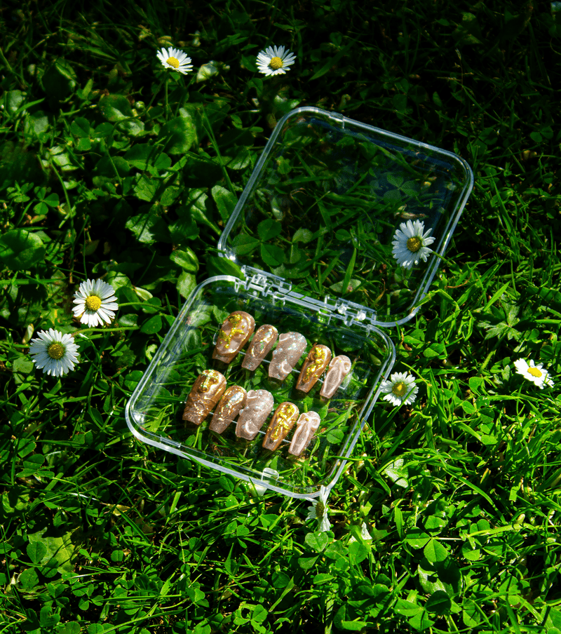 Golden Hour coffin press-on nails displayed in storage case on green background
