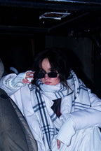 Model in a white puffer coat and sunglasses in a dark garage wearing beoopsie nails
