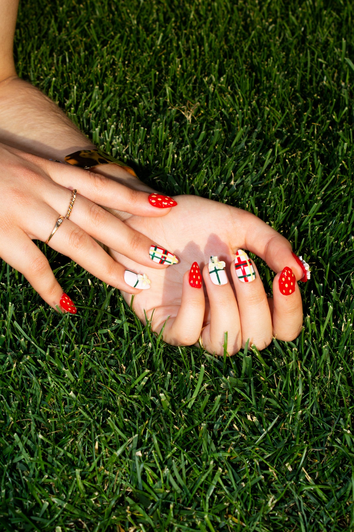 Wildflower Berries strawberry press-on nails on hands resting in green grass