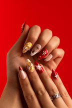 Starfall press-on nails with gold star charms and rhinestones on a red backdrop