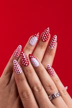 Ivory Cherries red and white polka dot press-on nails against a red backdrop