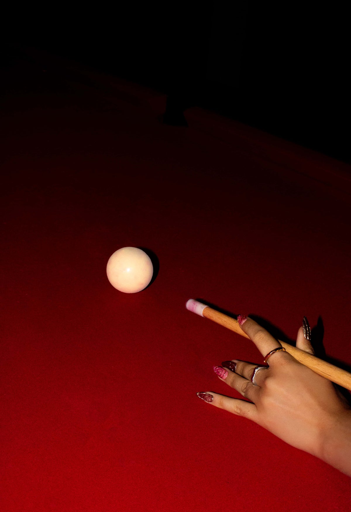 Hand with beoopsie press-on nails resting on a red pool table beside the cue ball