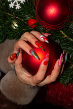 Hands in festive press-on nails cradling a red Christmas bauble