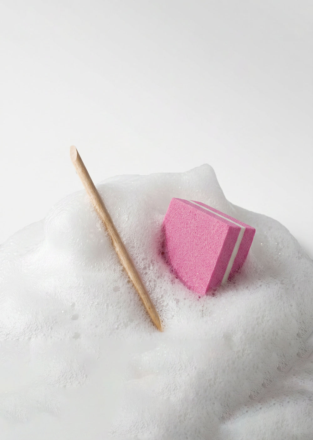 Cuticle stick and pink buffer from the beoopsie kit resting on soap foam