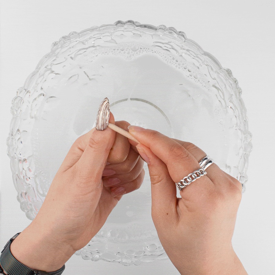 Easing off a press-on nail with a cuticle stick after soaking in warm water